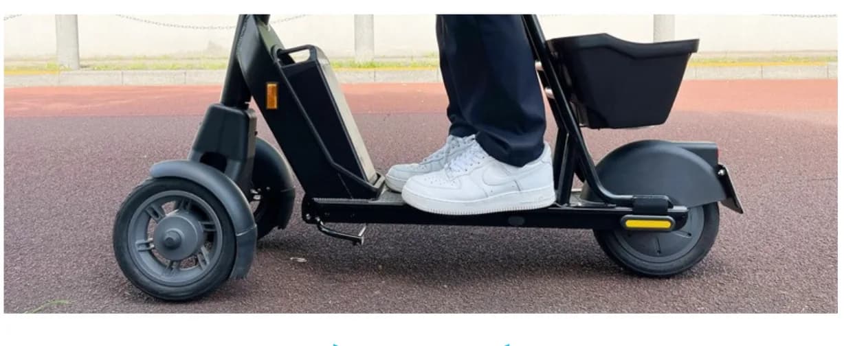 両足をボードに乗せて走っているところ。三輪の車体で、後ろにカゴが付いている。
