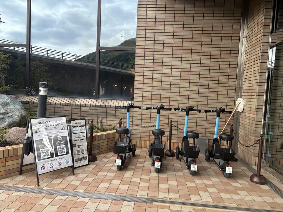 定山渓ビューホテルのポート。れんが色のタイル壁の前に TOCKLE が4台並び、手前に案内看板が置かれている