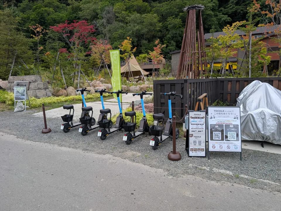 埜のてらすのポート。砂利敷きの一角に TOCKLE が6台並び、奥に色づいた木々とテント、木を組んだ塔が見える