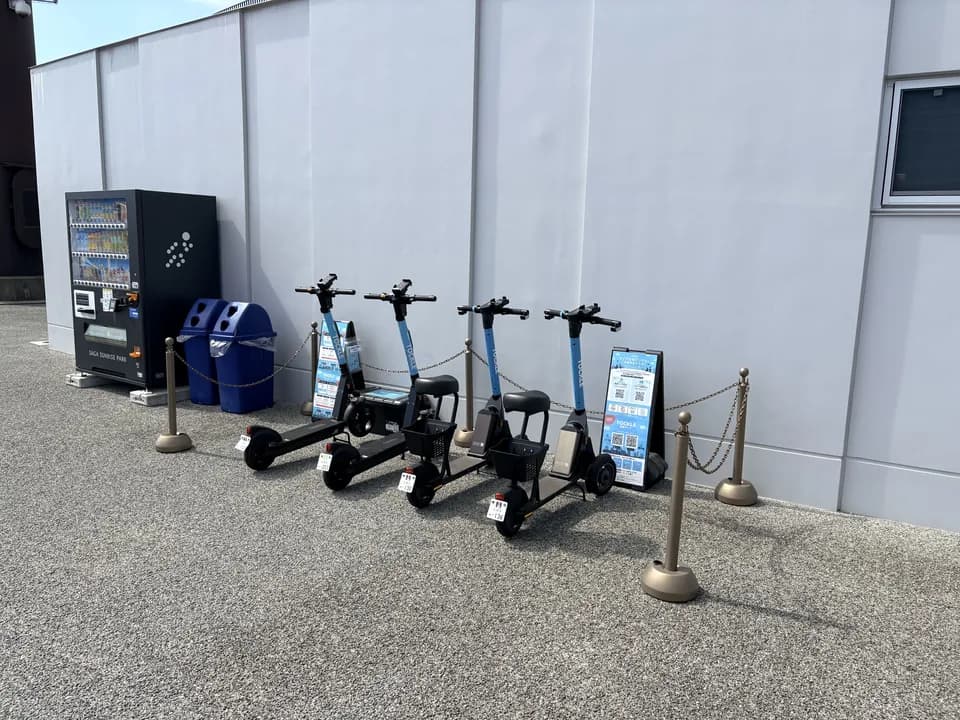 SAGAサンライズパークのポート。白い壁ぎわに TOCKLE が4台並び、左手に自動販売機と青いごみ箱が置かれている