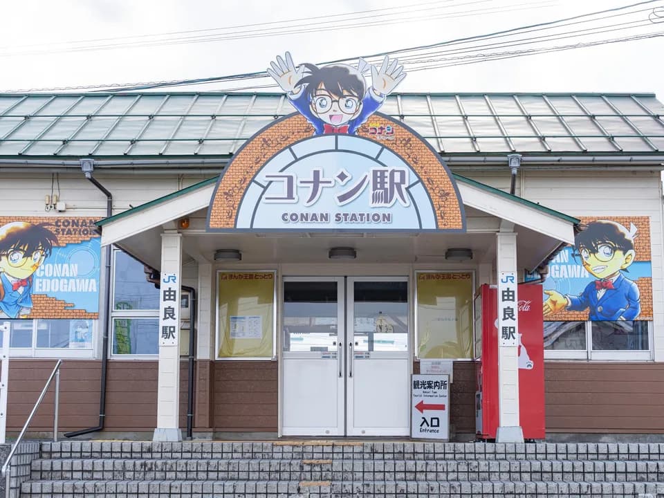コナン駅(JR由良駅)の駅舎正面。アーチ形の「コナン駅」の看板の上に両手を上げたコナンのパネル、左右の壁にキャラクターの大きな絵、柱に「由良駅」の表示