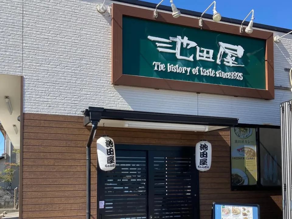 「池田屋」と白抜きされた深緑の看板を掲げた店構え。木目の壁に黒い引き戸、その両脇に屋号入りの提灯が下がる