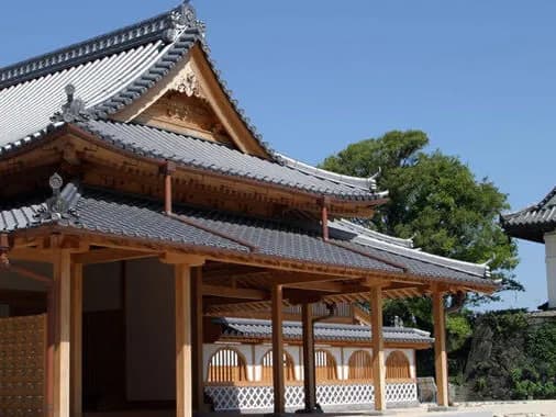 青空の下に建つ復元された本丸御殿。瓦屋根が幾重にも重なり、手前に木の柱が並ぶ縁側がのびる