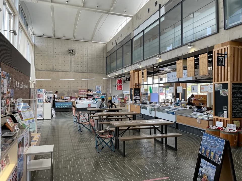 おみやげマーケットの店内。高い天井の下、木製の看板が並ぶ売り場と、テーブル・チェアが置かれた休憩スペース